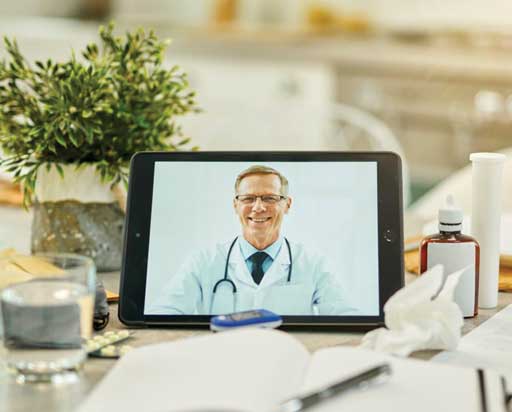 Digital tablet with an image of a medical doctor on it propped on a table full of medication